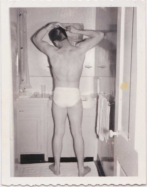 Vintage gay Polaroid Beefy guy standing in his underwear, combing his hair in front of the bathroom mirror