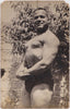 Real Photo Postcard of a beefy Egyptian strongman flexing in a walled garden