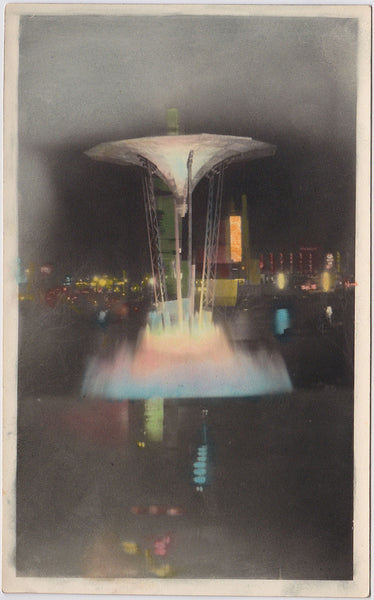 Beautiful hand-tinted image of an illuminated, sort of modernist fountain with colorful lights in the background.  5" x 7 3/4" vintage photo undated c. 1930s. Matt finish, fine condition.
