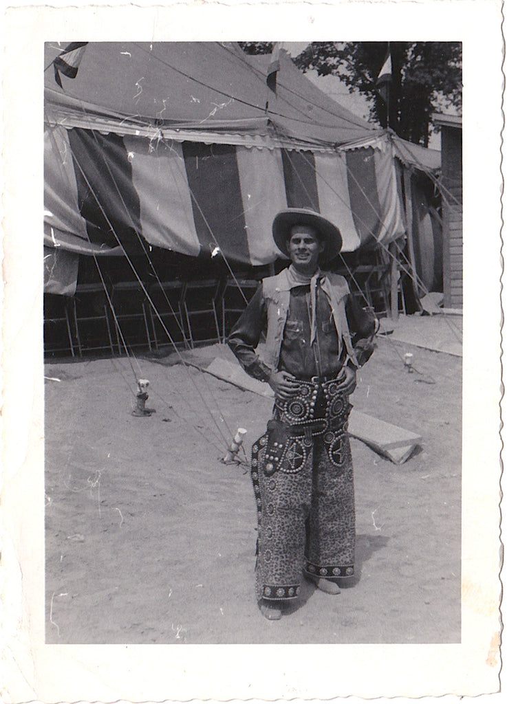 A man identified on the verso as "T.J." poses in costume near the tent. According to the note: the play is "Annie Get Your Gun."