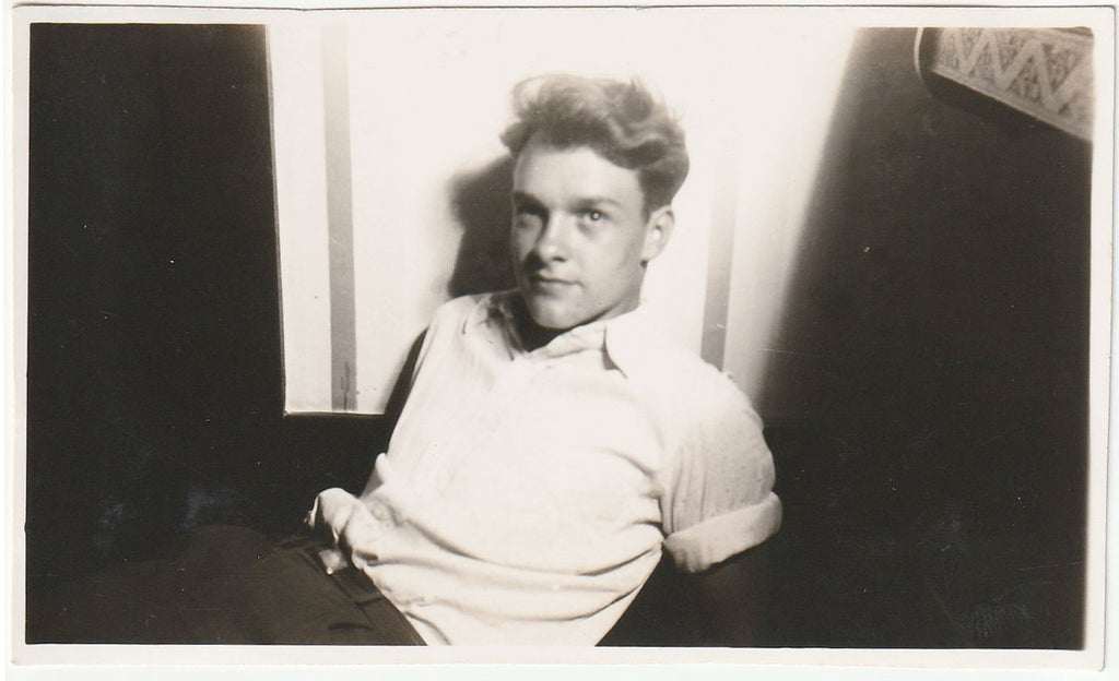 Handsome doe-eyed guy sits on the floor with his shirtsleeves rolled up.
vintage gay photo 1945.