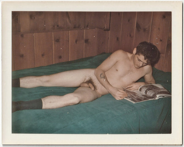 Male Nude Lying on bed looking at a straight porn magazine vintage gay Polaroid c. 1960s.