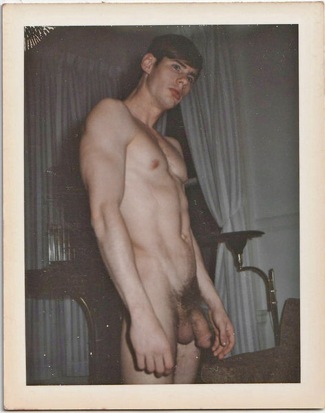 A vintage gay Polaroid of Big Bill Eld standing nude in the living room. 