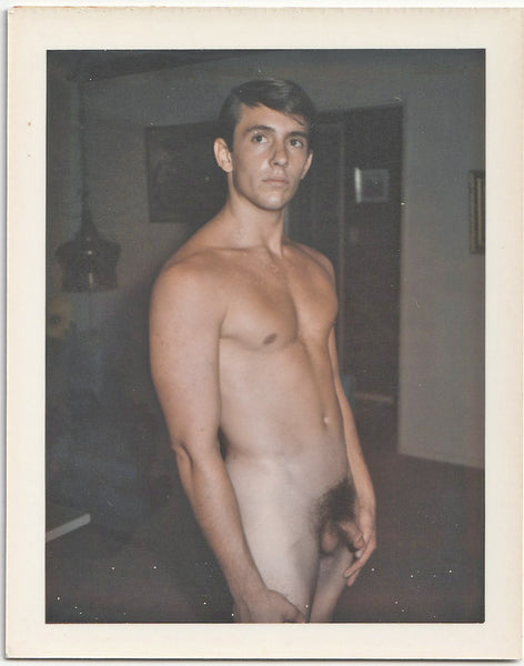 Male nude leans back slightly as he stands in the living room. 3 1/4" x 4 1/4" vintage gay Polaroid