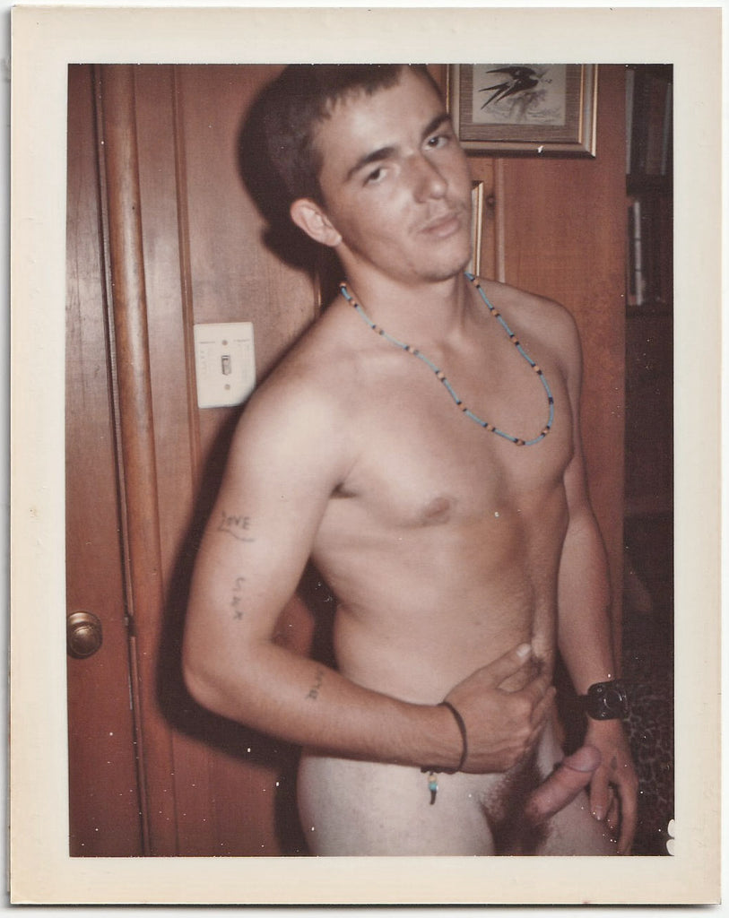 A vintage gay Polaroid of a male nude wearing a blue beaded necklace.