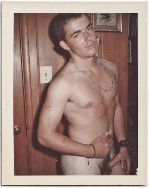 A vintage gay Polaroid of a male nude wearing a blue beaded necklace.