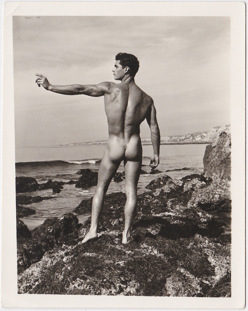 Stunning image of a lithe, dark-haired Forrester Millard standing on a rocky beach. Vintage physique photo.