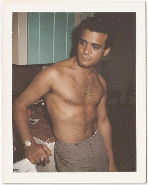 Dark and handsome guy leans against the kitchen counter sans shirt. vintage gay color Polaroid