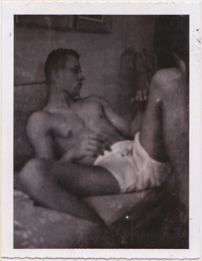 Vintage gay Polaroid, young man reclines on the bed. Moody and very suggestive.