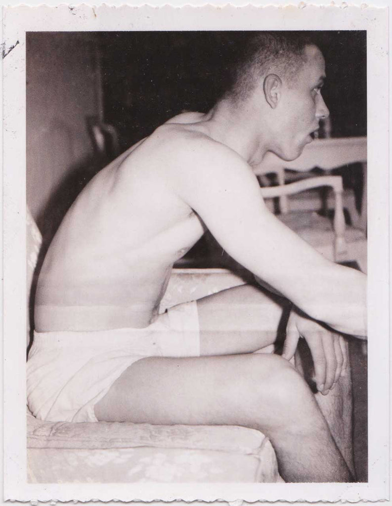 Vintage gay Polaroid, young man has removed his clothes except for his white boxers.