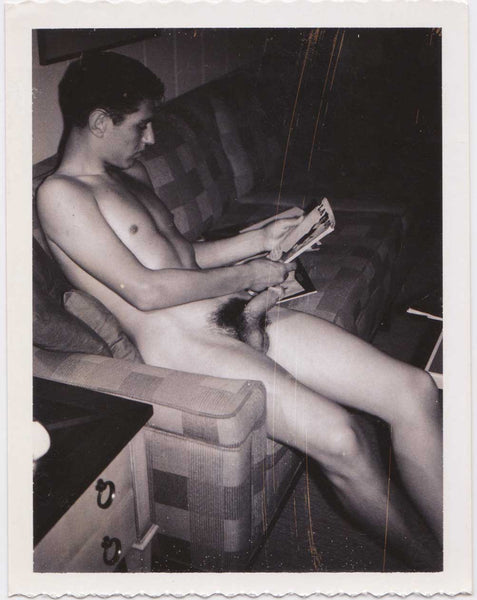 Vintage gay Polaroid Naked man sitting on the sofa, getting aroused by a Playboy magazine.