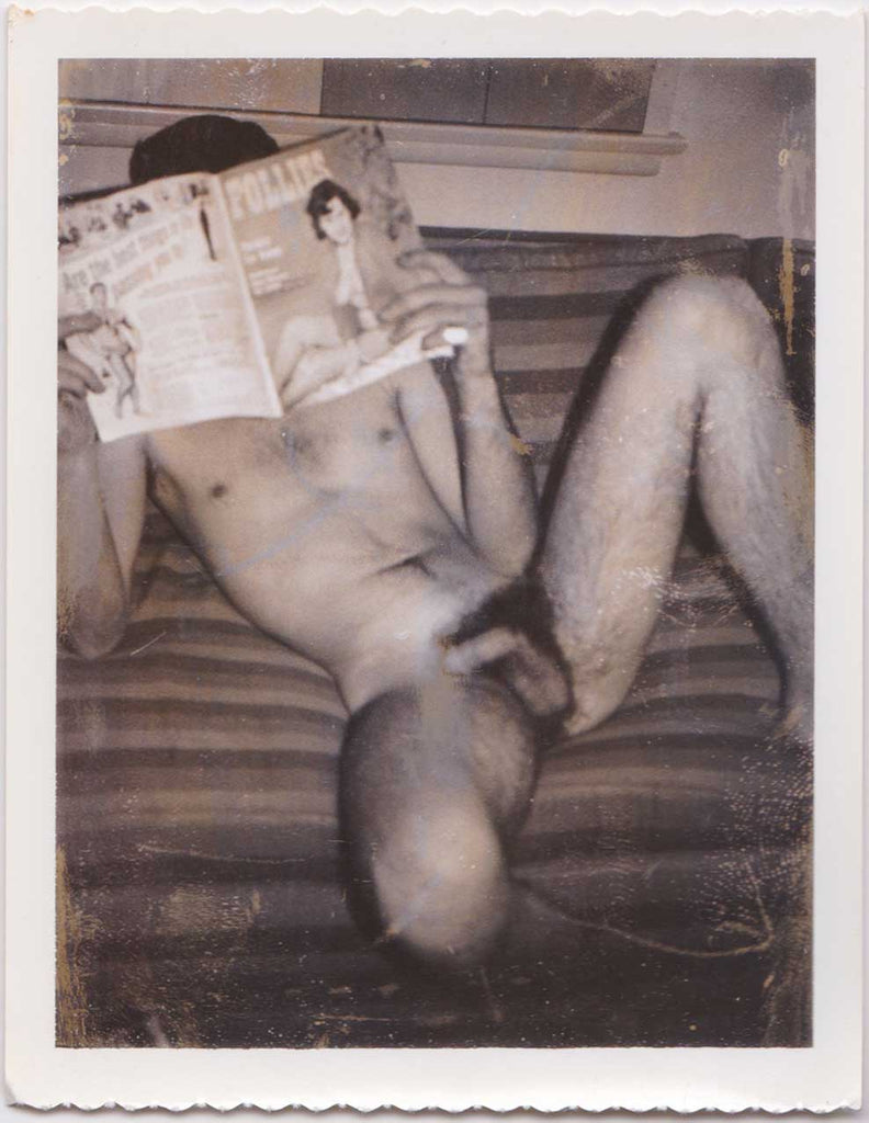 Naked man sitting on the sofa, his face hidden behind a Follies magazine. Vintage gay Polaroid