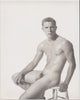 Handsome young athlete seated on a wooden stool. Vintage male nude