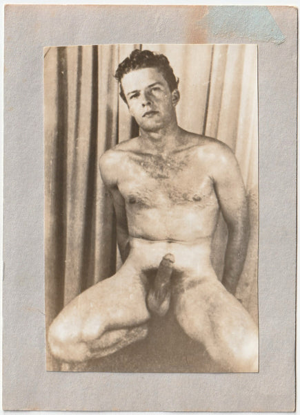 Handsome, hairy chested male nude poses before a curtain, vintage gay photo.