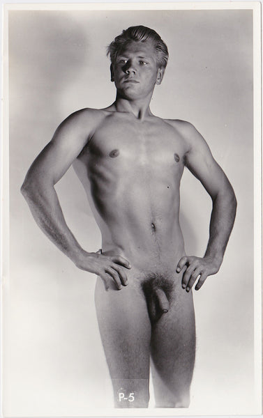Confident blond-haired guy stands in the studio with arms akimbo. vintage gay physique photo Calafran J. Brian