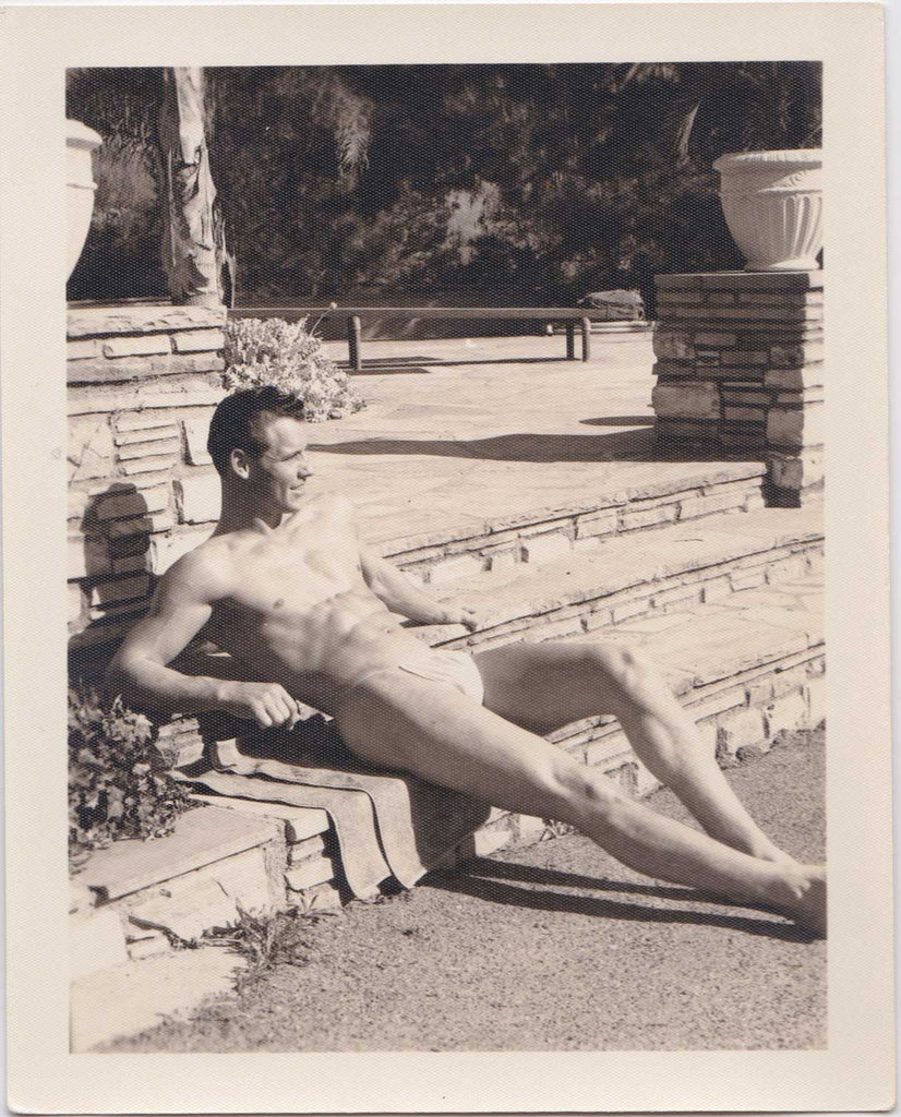 vintage gay photo Handsome man reclines on the stone steps wearing only a posing strap.