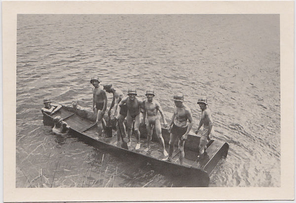 Vintage snapshot of six soldiers on a boat, two of whom are naked (except for their helmets) c. 1930s.