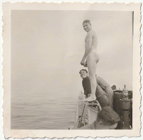 Beefy naked guy standing on the railing of a ship vintage gay snapshot.