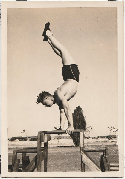 Good looking and muscular guy doing a handstand on parallel bars.