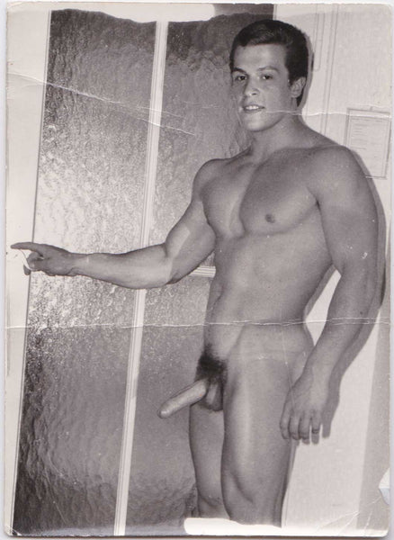 Vintage male nude Young Helmut Reidmeier reaches to turn a door latch. 