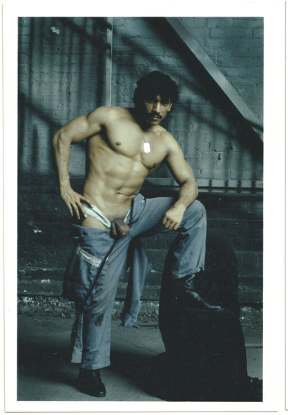 Tough guy strips to the waist in this vintage gay photo by Montreal-based photographer Carlos Quiroz (AKA Lobo Studios)