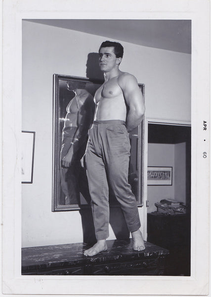 Handsome Luis stands shirtless on a table in front of a mirror.