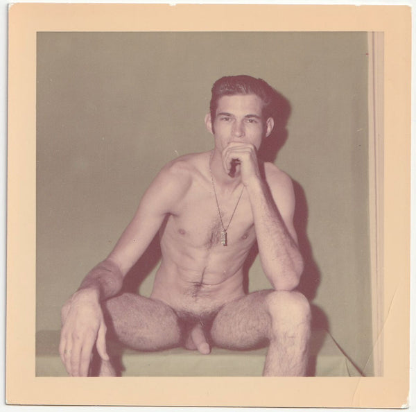 Handsome, hung, lanky guy with hairy legs rests his hand on his chin. vintage color snapshot c. 1970s.