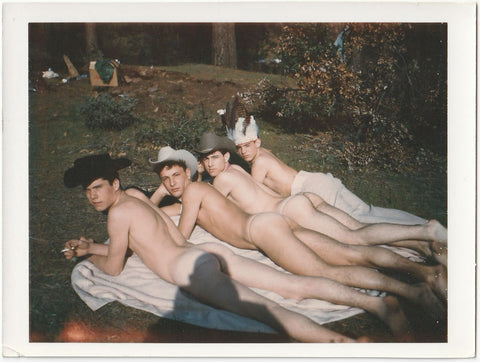 Four guys squinting at the hulking photographer as they lie nearly naked on a blanket. Three of them are "cowboys" and one appears to be an "Indian." vintage gay photo.