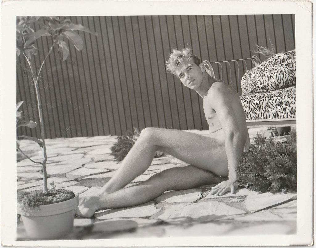 Handsome blond man reclines on a flagstone terrace. Vintage gay photo.