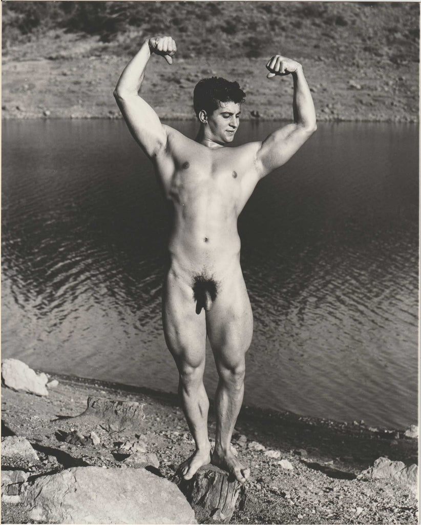 Original vintage photo of handsome Oakland weightlifter and cyclist Doyle Brewer flexing beside a river.