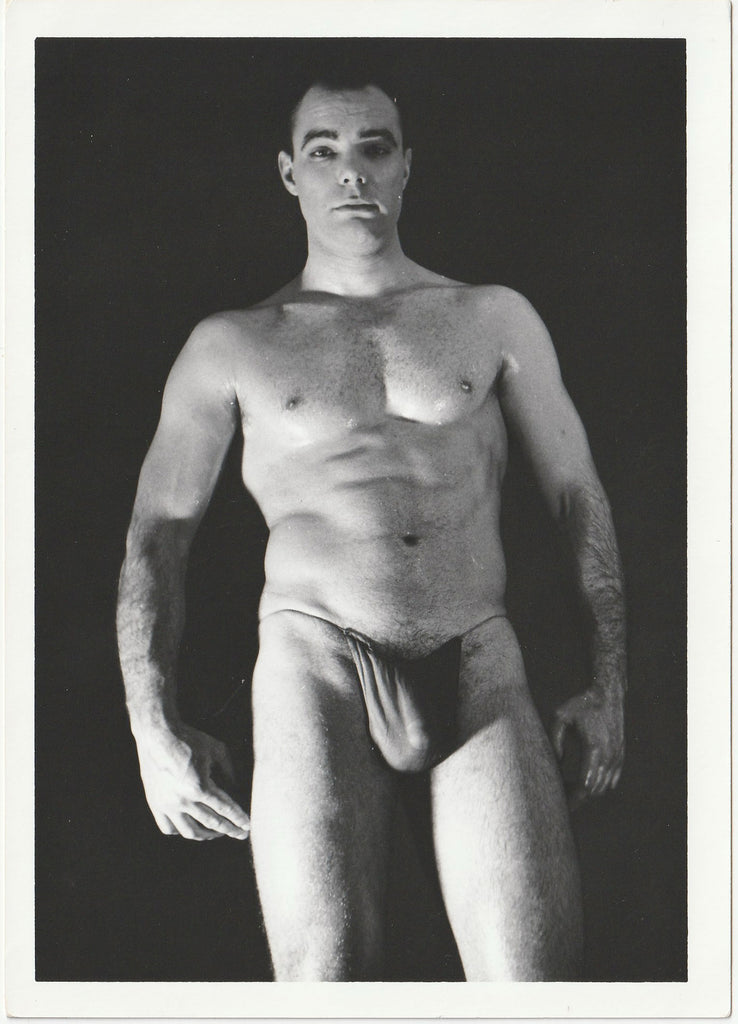 A black and white physique photograph of male model wearing a dark posing strap, Art Ullrich.