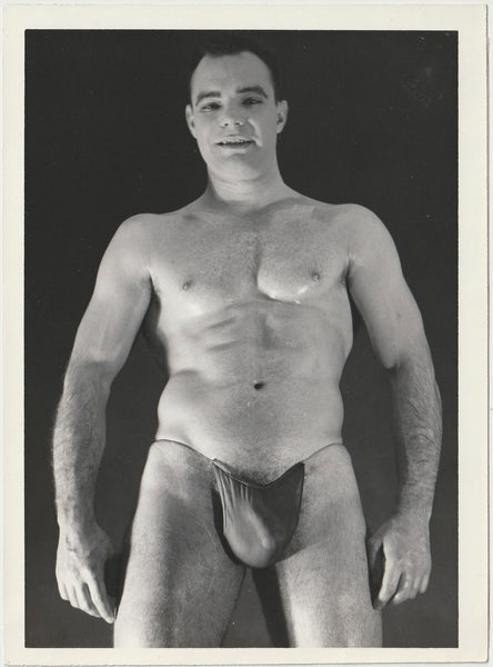 A black and white physique photograph of male model wearing a dark posing strap, Art Ullrich.