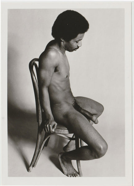 A black and white fine art photograph of a seated nude male figure on a wooden chair, attributed to Sierra Domino c. 1970s
