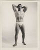 A black and white vintage physique photograph of a muscular man posing in a jockstrap by Bruce of LA.