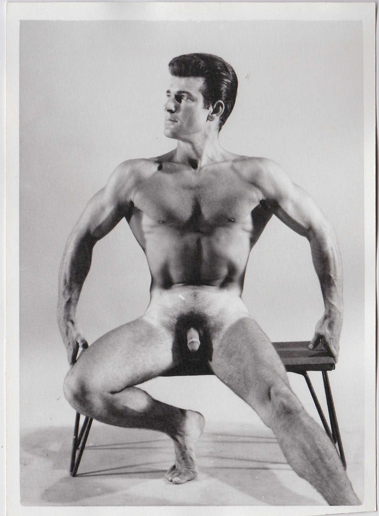 Vintage physique photo of handsome dark-haired Reno sitting on a low bench.