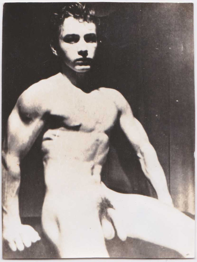 Seated male nude with a somber expression.