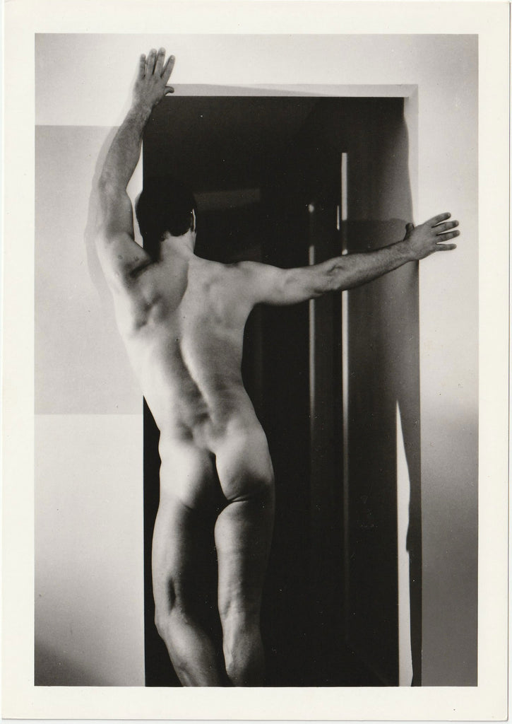 Unidentified male nude posing with arms extended across a doorway vintage Target Studios physique photo.