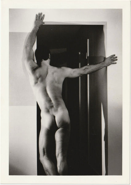 Unidentified male nude posing with arms extended across a doorway vintage Target Studios physique photo.