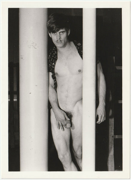 Handsome John Converse (AKA Dak) stands behind some big metal poles vintage gay photo by Target Studios.