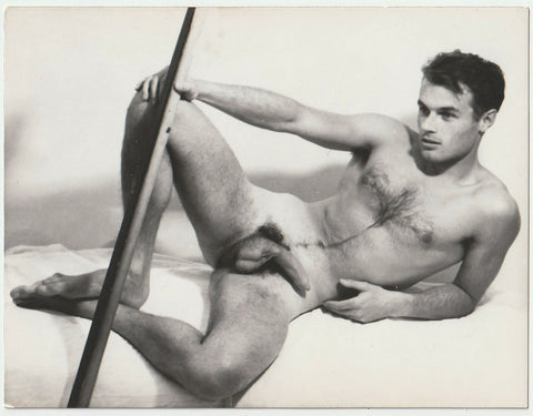 Handsome Yves Le Cadou reclines while holding some sort of rod 3 1/2" x 4 1/2" print on gloss paper, no studio marks, c. 1960.
