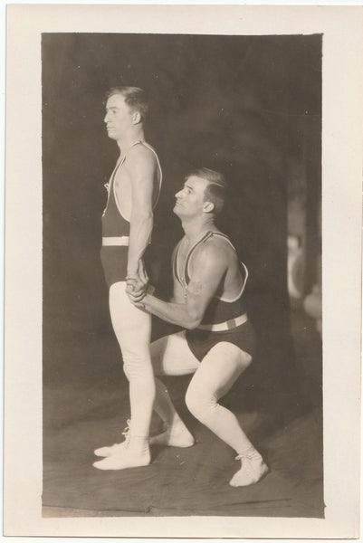 Vintage photo Bottom man squats as he grabs the top guy's wrists in preparation for a lift.