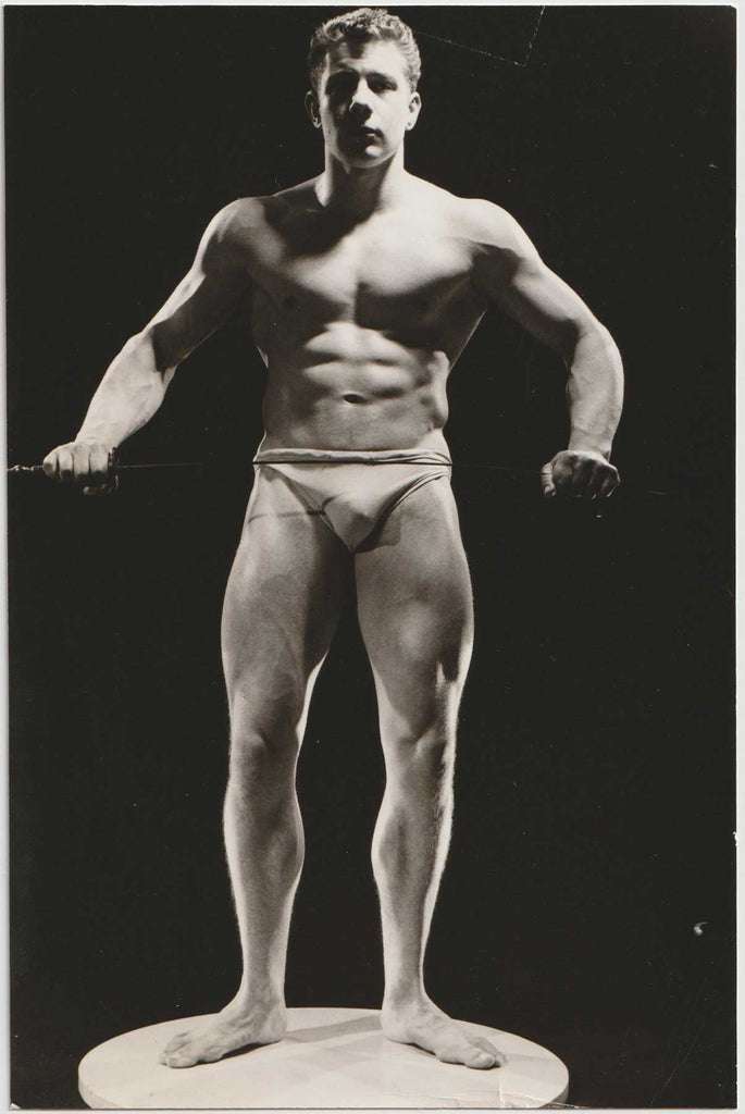 Rare vintage photo by Royale, London, of a dramatically lit bodybuilder holding a sabre. 