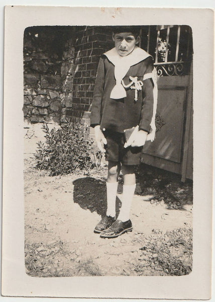Vintage black and white photo of a person in formal attire standing outdoors.