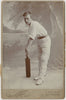 Vintage photograph of a handsome man holding a cricket bat  in a studio setting.