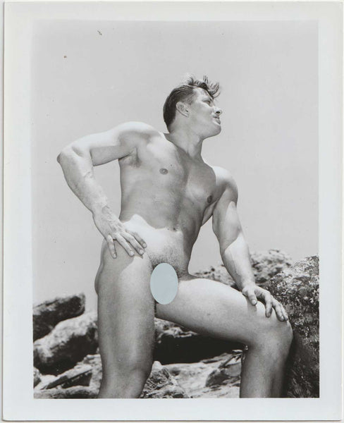 Vintage photo of handsome Dave Lancaster standing against a background of boulders.