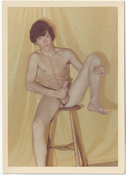 Lithe dark-haired nude seated on stool holding his dick and one knee. Vintage gay photo