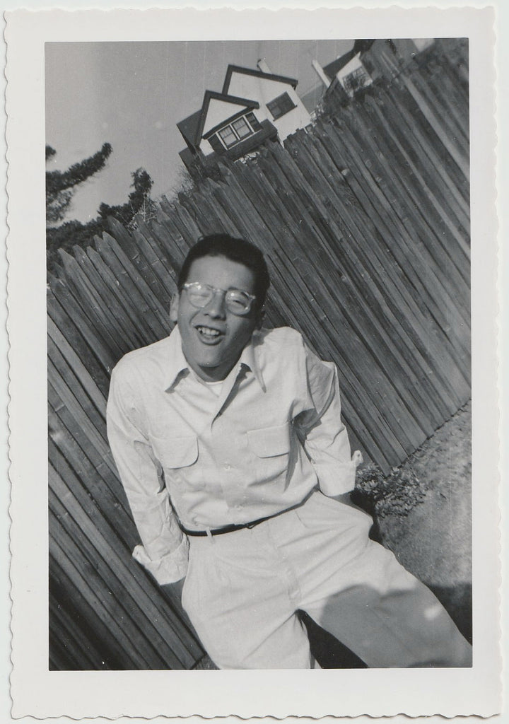 Everything's at an angle in this vintage photo of a bespectacled young guy in white vintage snapshot.