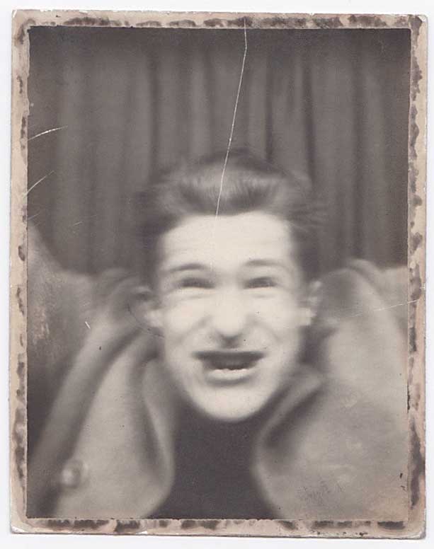 Blurry vintage photo booth photo of a young guy acting crazy.