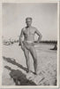 Man in belted swimsuit identified on verso as "Claude Leslie" in a contrapposto position.