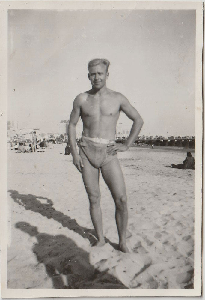 Man in belted swimsuit identified on verso as "Claude Leslie" in a contrapposto position.